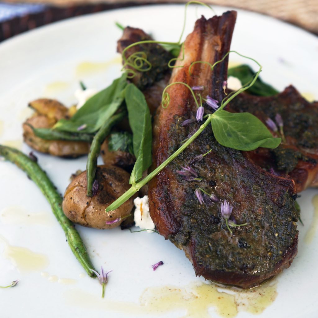 Ras el hanout lamb chops served with roasted potatoes and green beans garnished with chive flowers. 