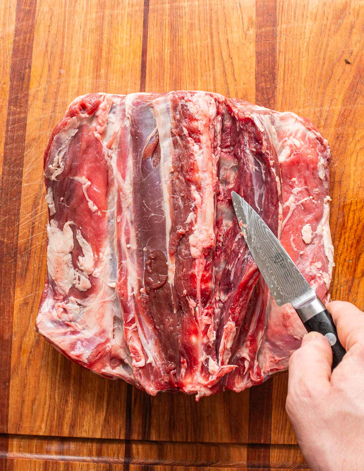 Removing the tenderloins from a lamb saddle with a paring knife.