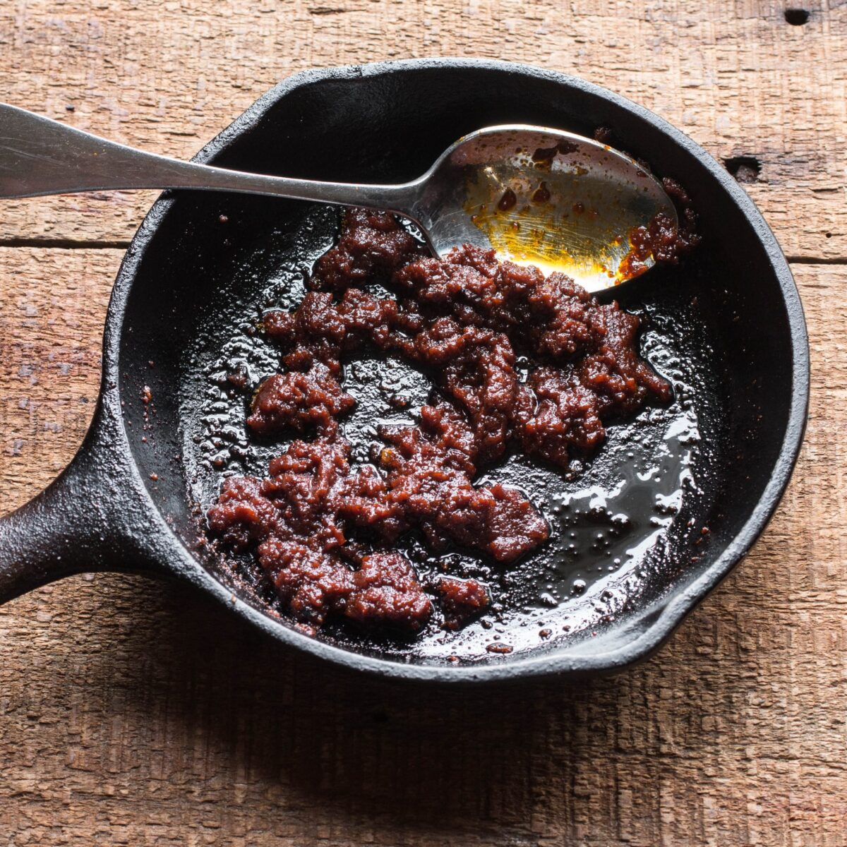 Cooking harissa paste in a small cast iron skillet.