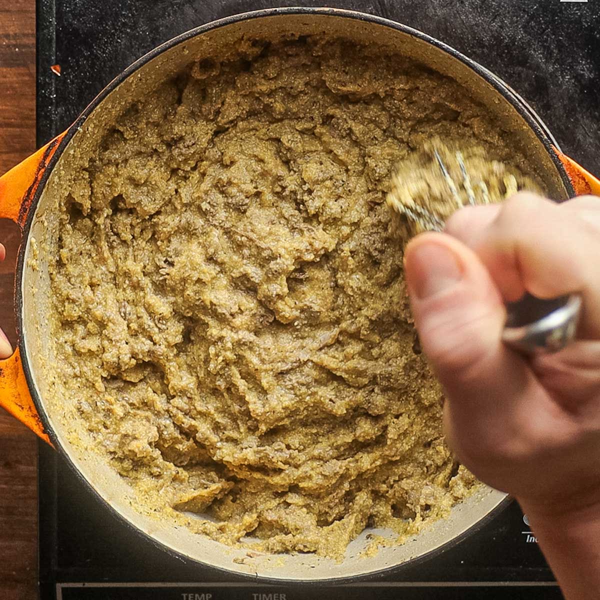 Mashing cooked liver and cornmeal with a whisk.