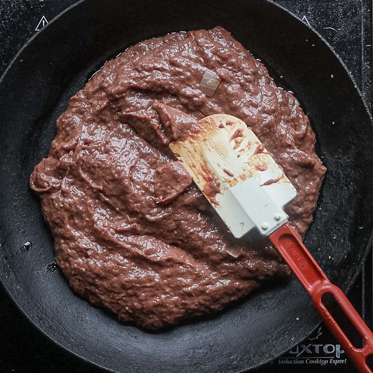 Liver mixture being cooked in a pan stirred with a spatula.