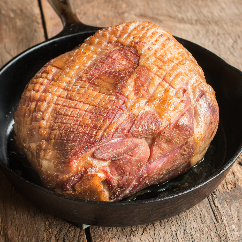 A smoked leg of lamb baking in a cast iron pan.