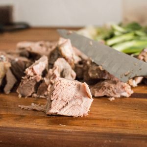 Cutting cooked lamb shoulder into chunks