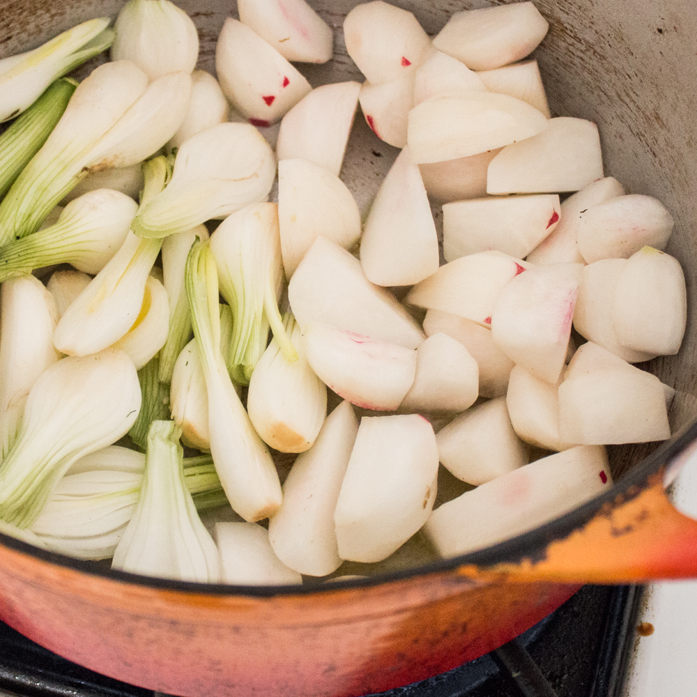 Cooking scallions and turnips in a pot.