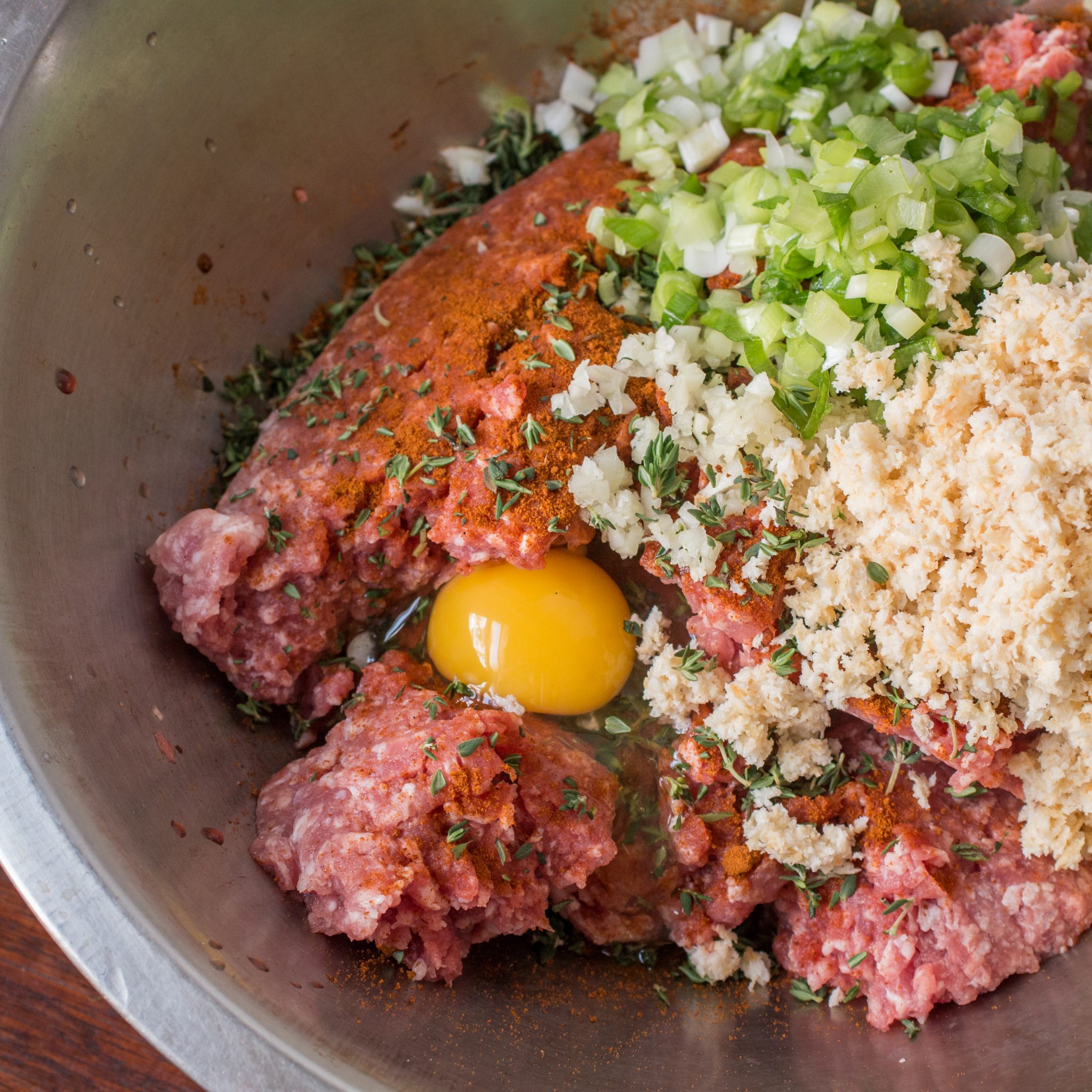 Mixing eggs and breadcrumbs into lamb meatloaf mixture in a bowl.