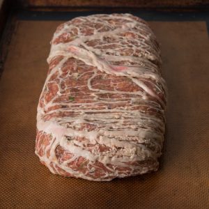 Lamb and goat bacon meat loaf formed and wrapped in , caul fat