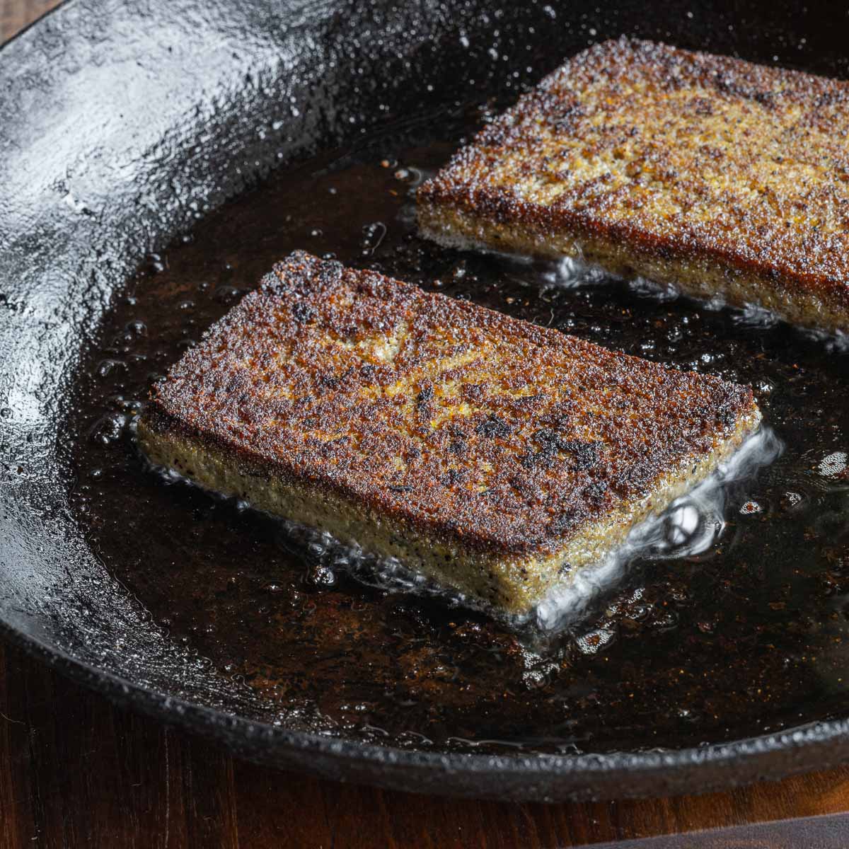 Golden brown scrapple fried in a pan.