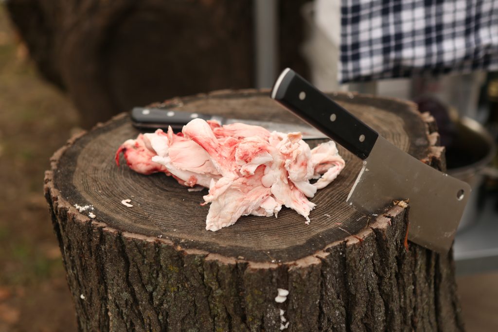 Trimming fat from a whole lamb to prevent grill flare ups.