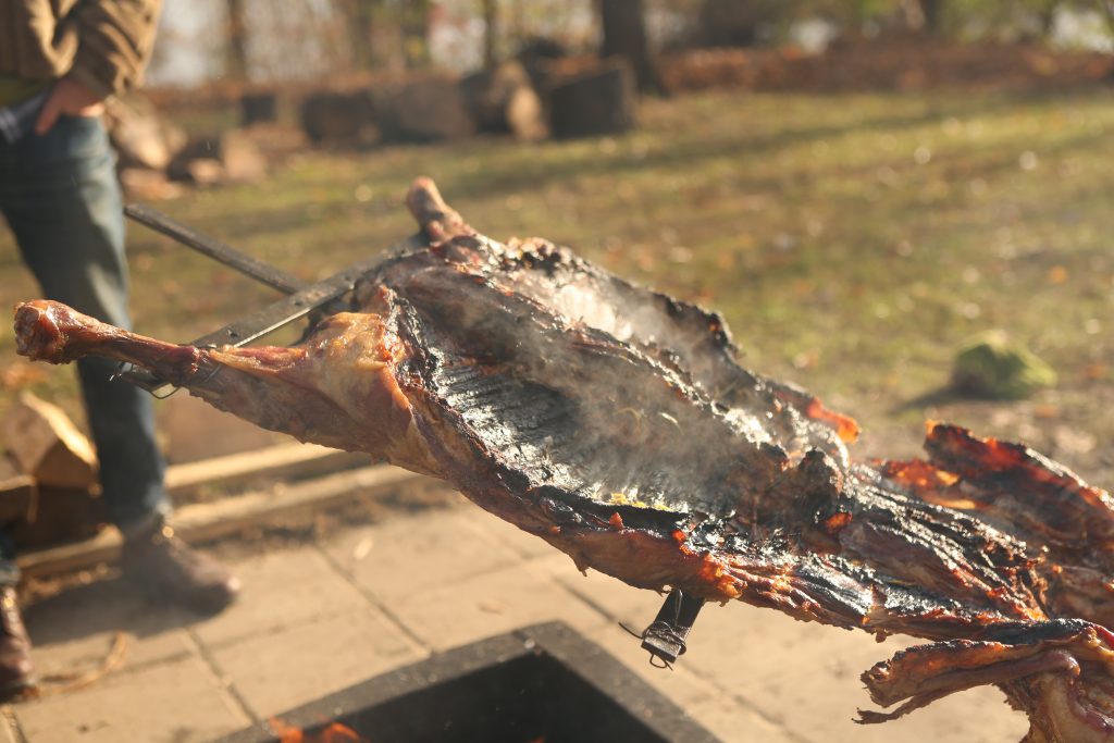 Rotating the lamb on the asado cross to finish the skin side.