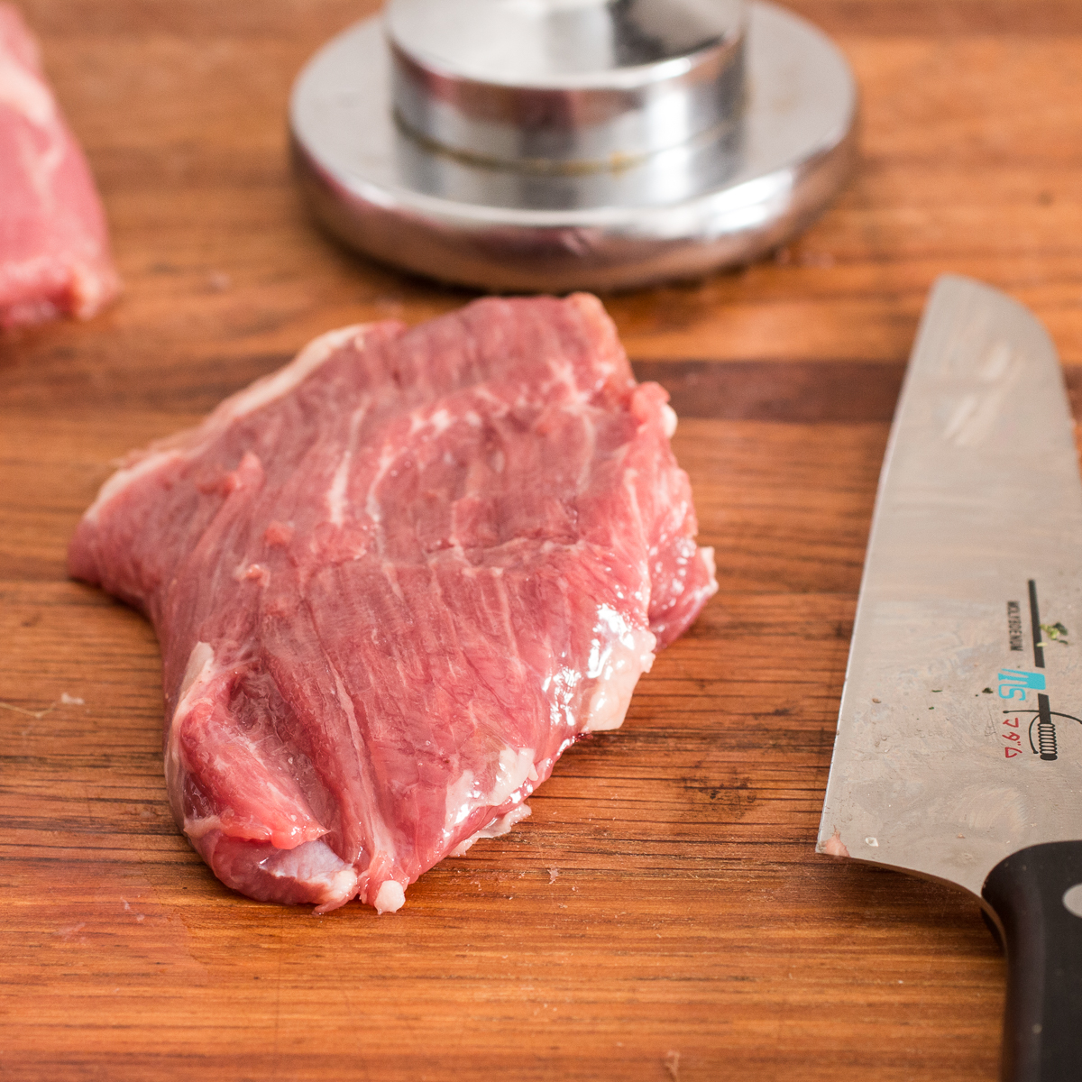A thick slice of lamb loin next to a knife.