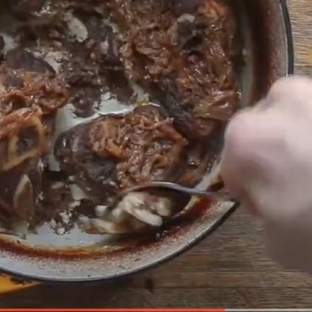 Removing the fat from cooked lamb shanks.