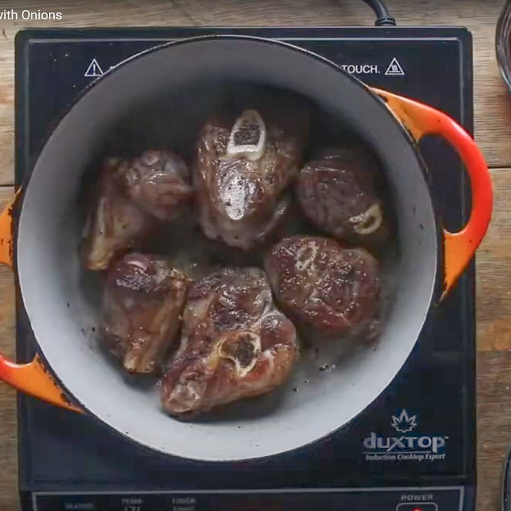 Browning lamb shanks in a pot.