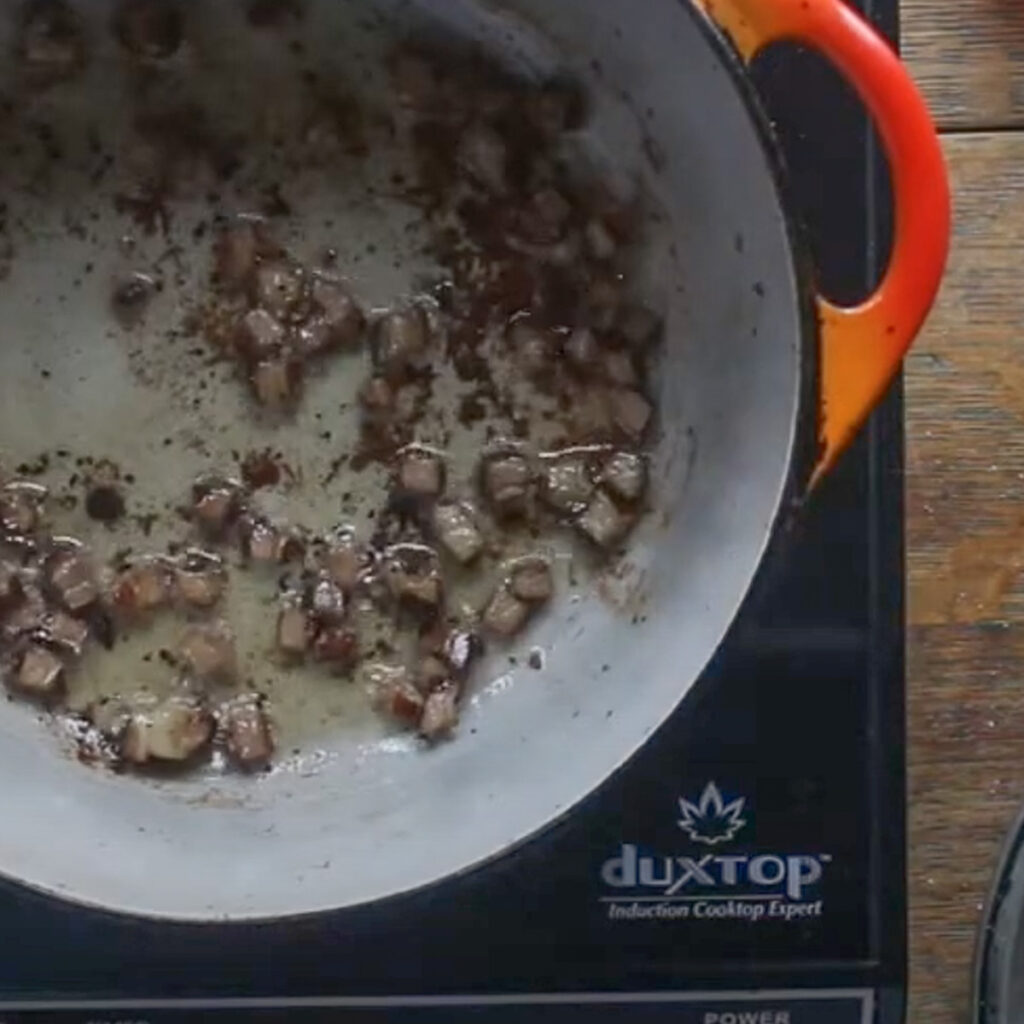 Browning lamb bacon in a pot to remove the fat.