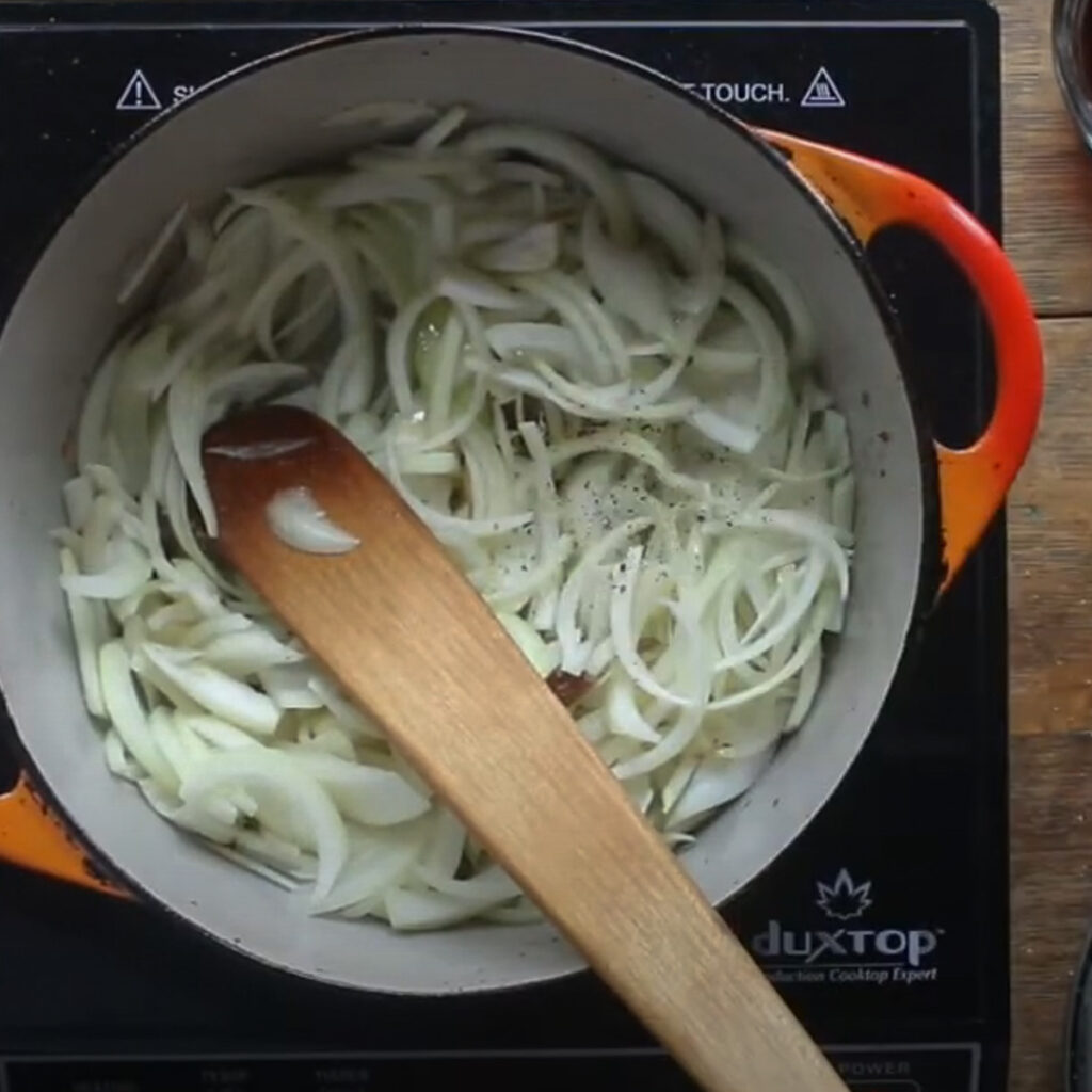 Adding onions to a pot to make caramelized onions.