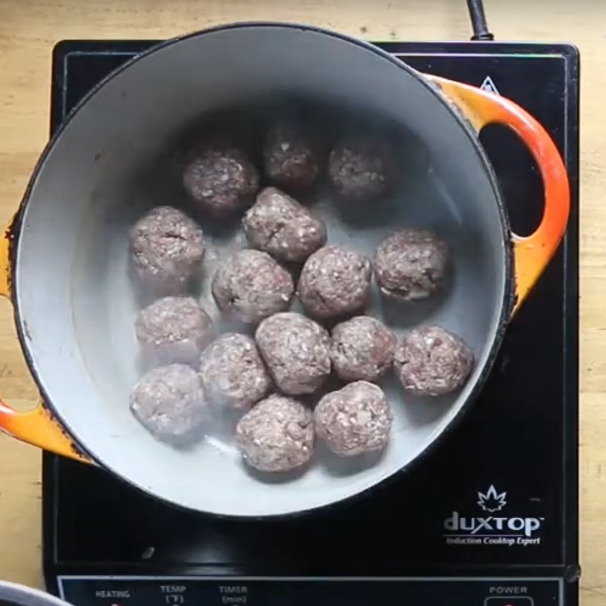 Browning lamb meatballs in a pot.