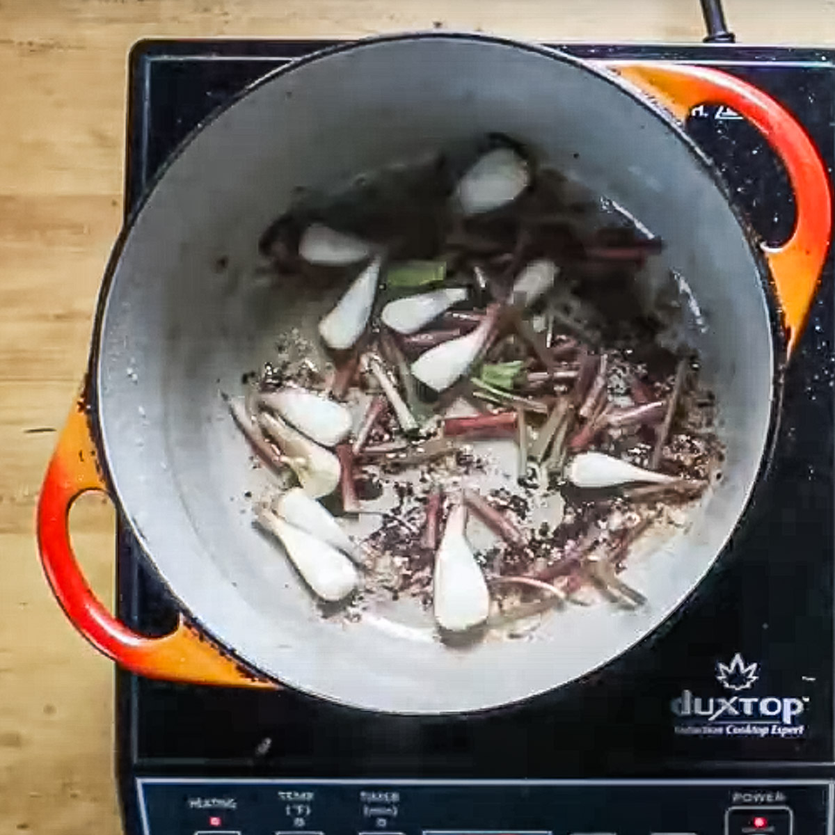 Cooking ramps or spring onions in a pot for lamb meatball soup.