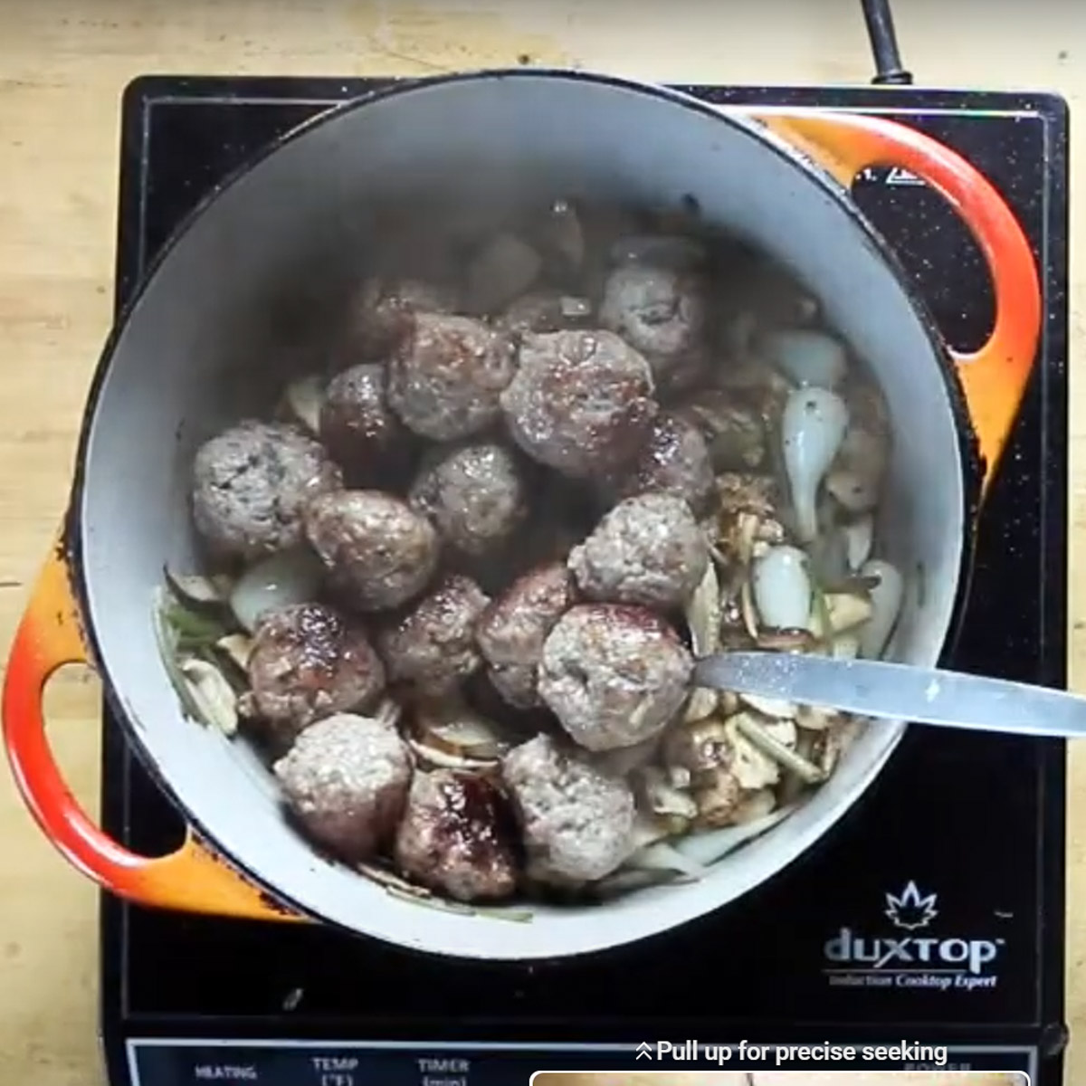 Adding meatballs to a pot of soup.