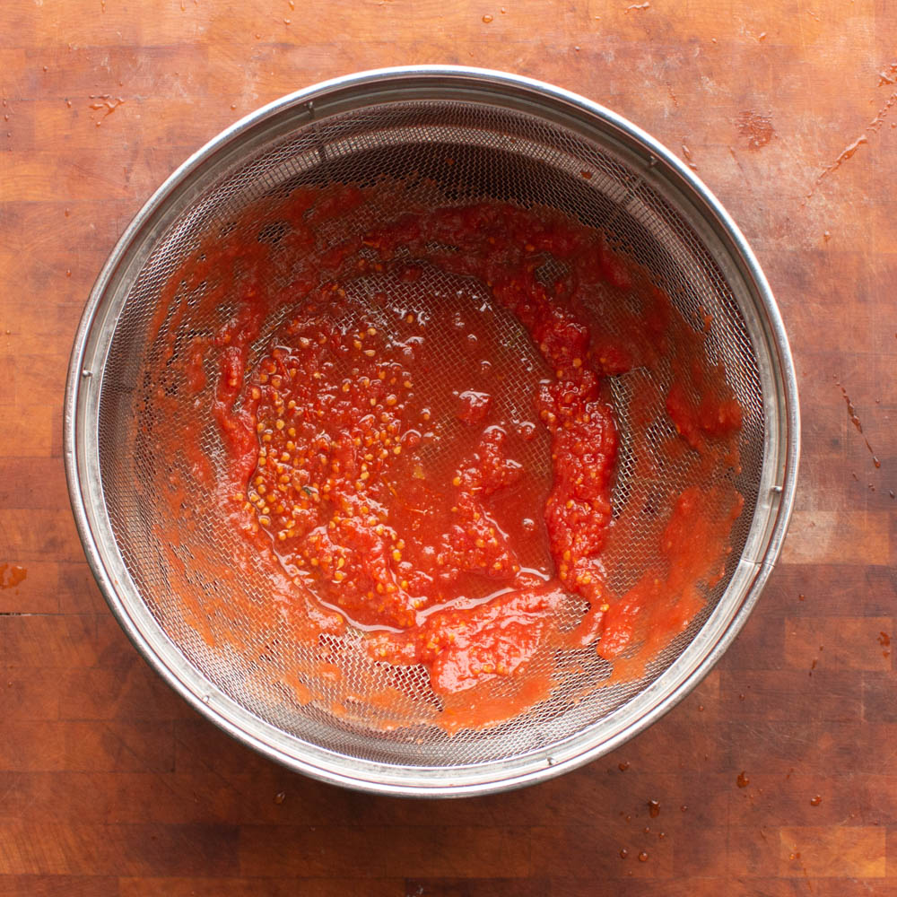 Pass pureed canned tomatoes through a strainer.