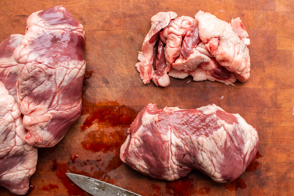 cutting the fat off the top of a lamb or goat heart 