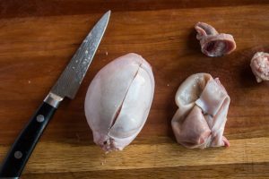 trimming lamb or goat testicles on a cutting board
