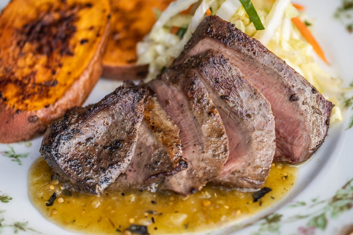 sliced grilled lamb heart with salsa verde sweet potatoes and cabbage slaw
