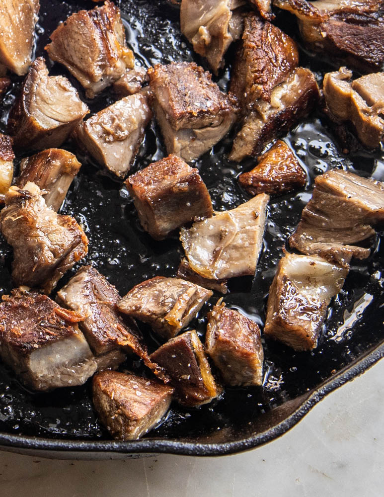 Frying goat shank meat in a pan
