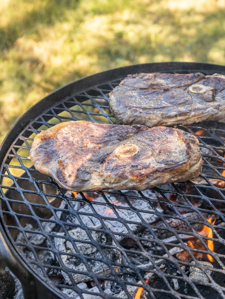 Grilling lamb leg steaks over a wood fire. 