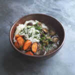 goat neck stew in a bowl with carrots, mashed potatoes, horseradish and parsley