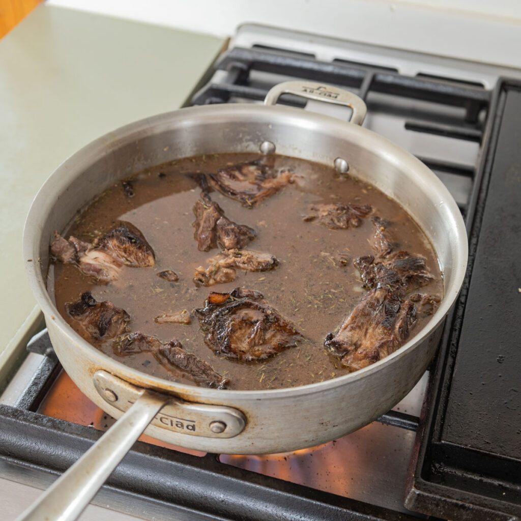 cooking goat neck stew in a wide satoir pan
