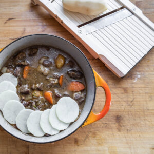 covering stew with sliced potatoes in a dutch oven