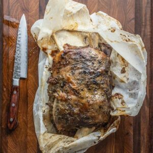 Removing a smoked lamb shoulder from parchment paper.