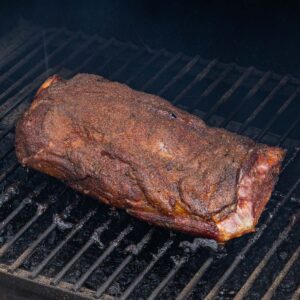 A lamb shoulder cooking in a smoker.