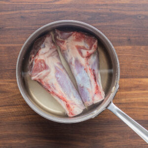 A top-down picture of lamb shanks in a brine.