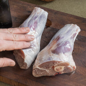 Rubbing lamb shanks with cooking oil.
