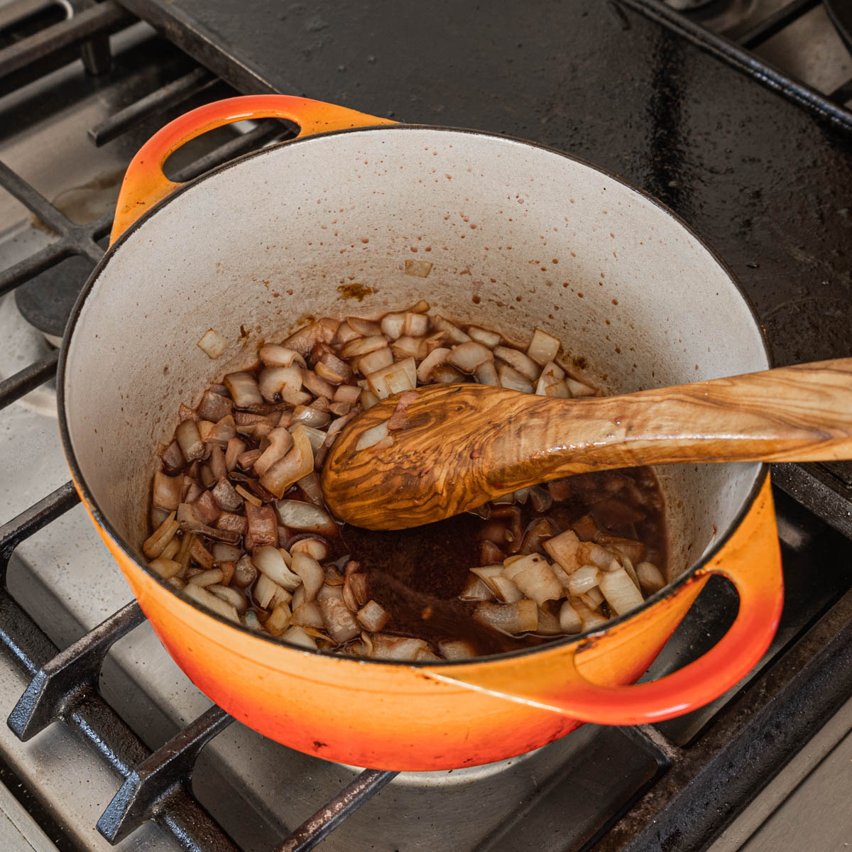 Adding red wine to a pan of onions browned in lamb drippings.