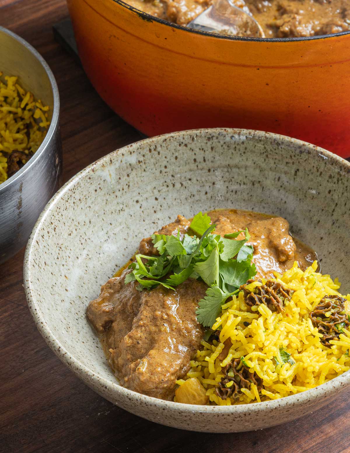 Mutton korma in a bowl served with Indian mushroom rice, garnished with cilantro. 