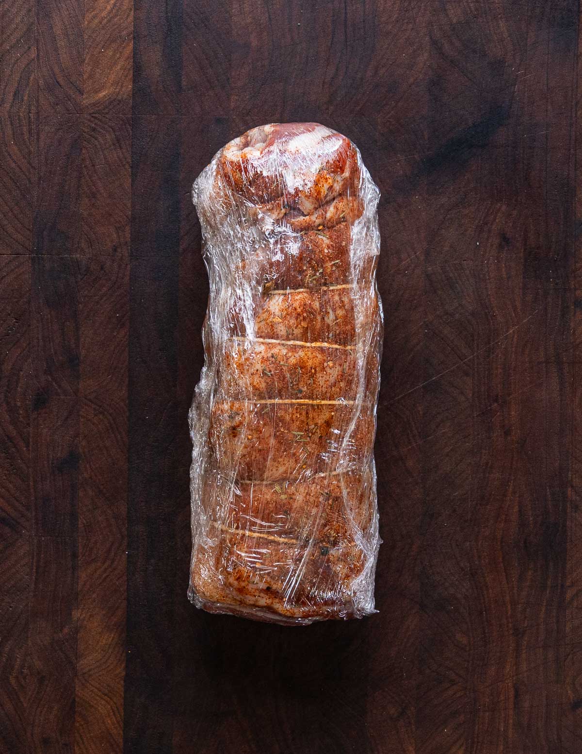 Wrapping a lamb breast in cling film after smoking to keep it moist.