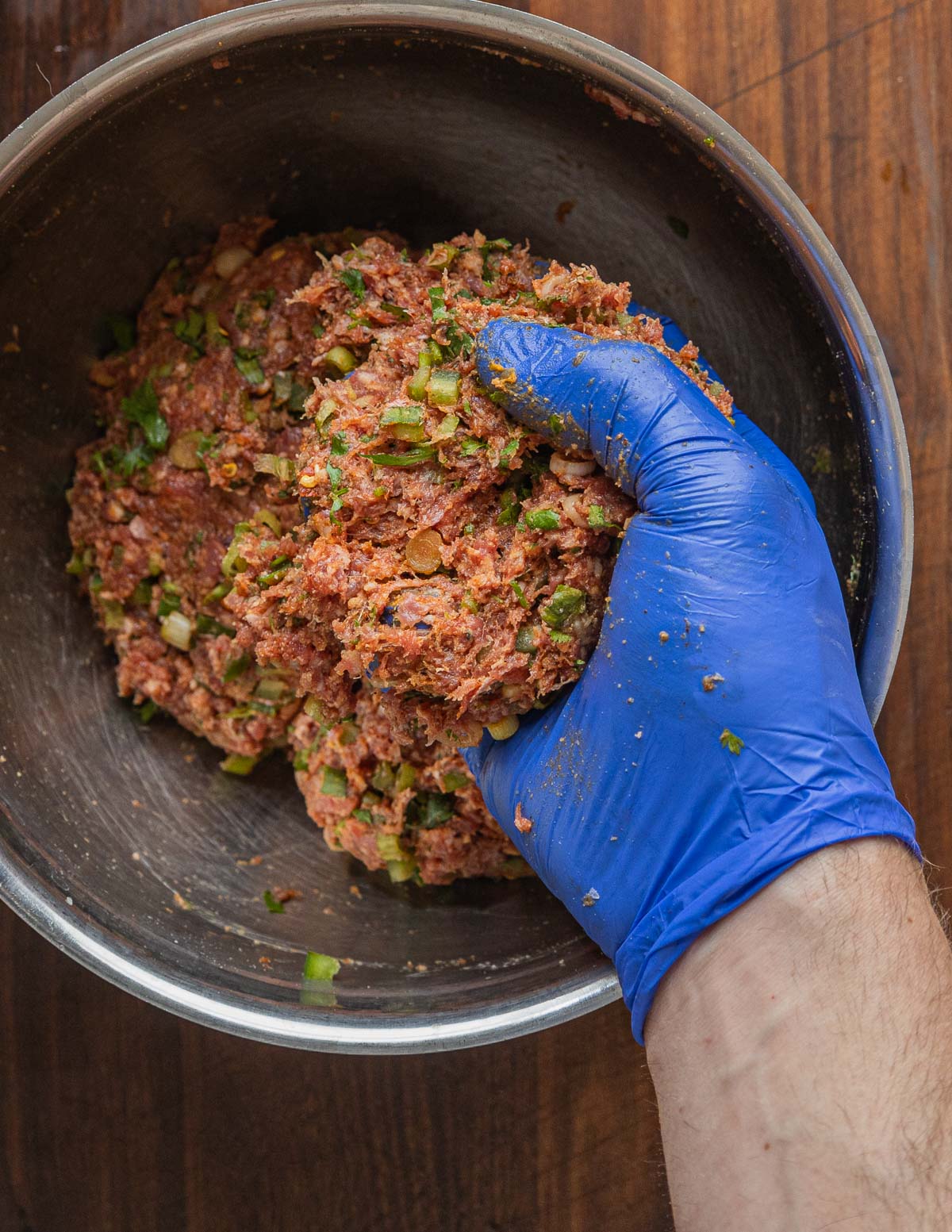 mixing meatball mixture with gloved hands.