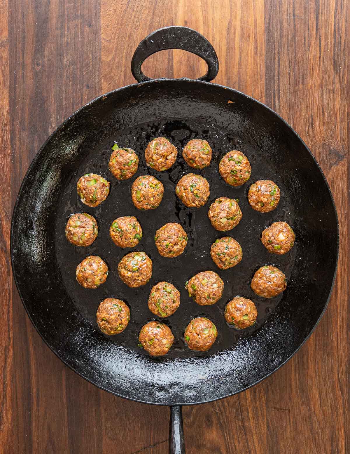 A pan of raw meatballs ready to cook in a Kehoe carbon steel pan.