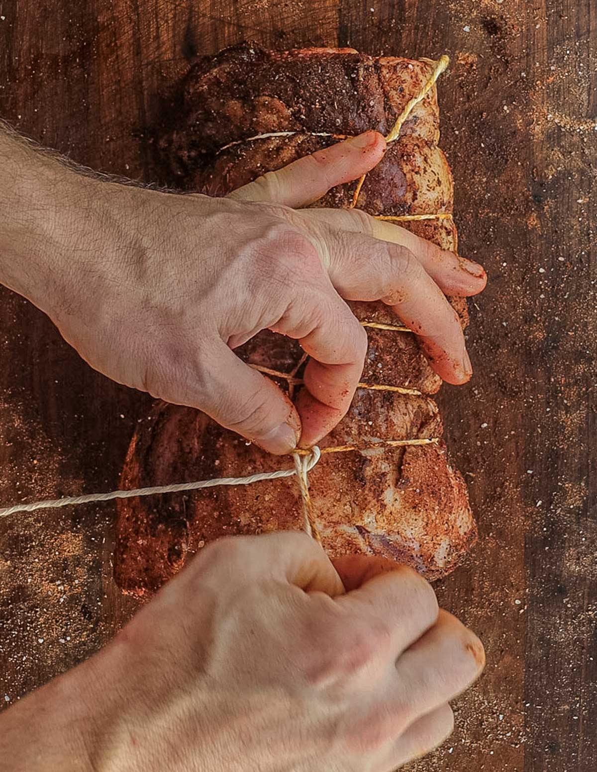 Tying a seasoned boneless leg of lamb with butchers twine.