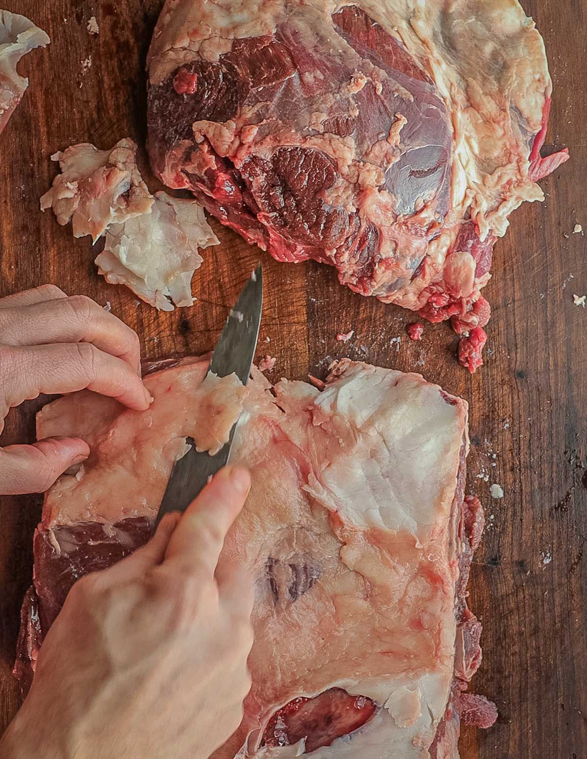 Trimming and removing the fat from a leg of lamb.